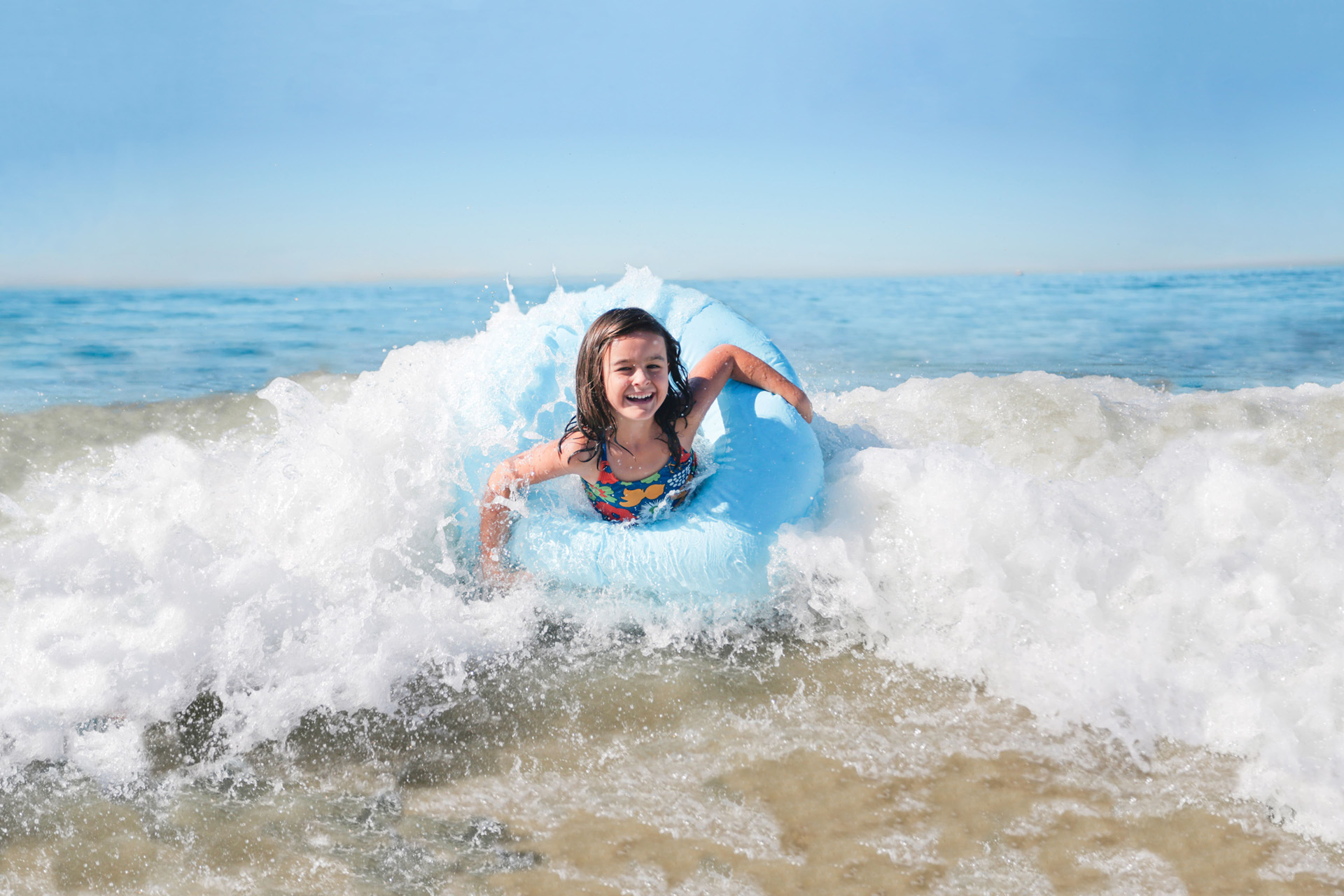 girl riding a float in the surf